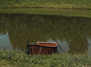 un petit bateau assis au milieu d'une masse d'eau dans l'établissement Laumių Nameliai, à Anykščiai