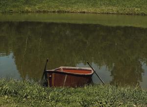 a small boat sitting in the middle of a body of water at Laumių Nameliai in Anykščiai