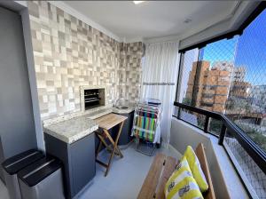 a room with a balcony with a counter and a table at Apartamento Decorado Coral in Balneário Camboriú