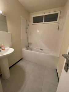 een badkamer met een wit bad en een wastafel bij Studio aux portes de Paris in Chatou