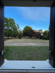 een open raam met uitzicht op een veld met bomen bij Studio aux portes de Paris in Chatou