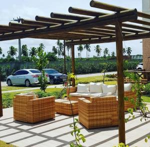 a patio with wicker seating under a wooden pergola at MURO ALTO COND CLUBE Bl4 413 in Ipojuca