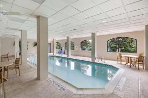 a swimming pool in a room with a table and chairs at SureStay Plus Hotel by Best Western Houston Medical Center in Houston