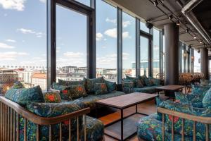 Habitación con sofás, mesas y ventanas grandes. en Scandic Hamburger Börs, en Turku