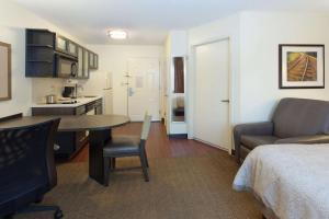 a room with a bed and a table and a kitchen at Sonesta Simply Suites Wichita Airport in Wichita