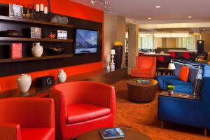 a living room with red chairs and a television at Sonesta Select Birmingham Colonnade in Birmingham