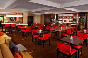 a restaurant with tables and red chairs and a bar at Sonesta Select Birmingham Colonnade in Birmingham