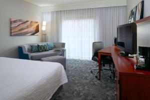 Habitación de hotel con cama y escritorio con TV. en Sonesta Select Kansas City Airport Tiffany Springs en Kansas City