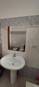 a bathroom with a sink and a mirror and a toilet at Casa Vacanza alloggio Casa Maria in Sennori