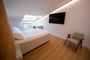 a bedroom with a bed and a tv and a chair at Hotel Boutique Berazadi Berri in Zarautz