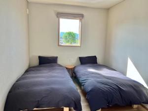 Furano Yayoi-house　 في فورانو: سريرين في غرفة صغيرة مع نافذة