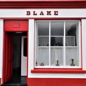 Un edificio rosso e bianco con una finestra con un cartello che legge "Blaze" di Blakes in Carrigaholt a Kilkee