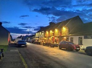 a street with cars parked in front of a building at Blakes in Carrigaholt in Kilkee