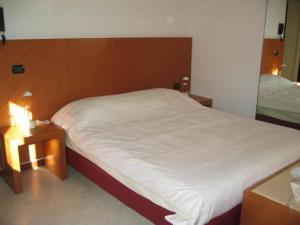 1 dormitorio con 1 cama blanca grande y 2 mesas en Residence Il Rampicante, en Monticelli Terme