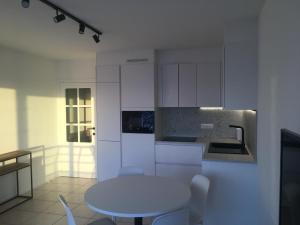 een witte keuken met een tafel en een wastafel bij Studio 4 pers met Frontaal Zeezicht & privé zwembad Oostende in Oostende