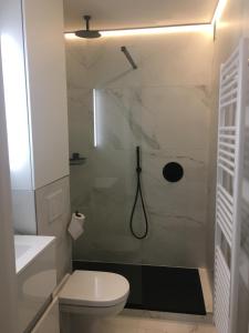 een witte badkamer met een douche en een toilet bij Studio 4 pers met Frontaal Zeezicht & privé zwembad Oostende in Oostende