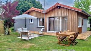 a wooden cabin with a table and chairs and an umbrella at Le Cosy Porgeais in Le Porge