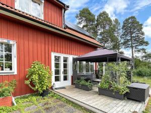 a red house with a wooden deck with an umbrella at 6 person holiday home in VRETA KLOSTER in Vreta Kloster