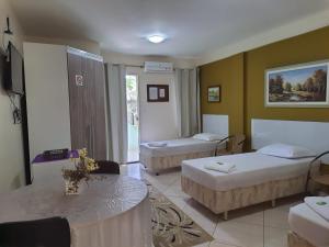 a hotel room with two beds and a table at Pousada Alto Riviera in Macaé