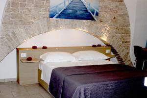 una camera con un letto e un muro in pietra di Rubis Relais & SPA a Ruvo di Puglia