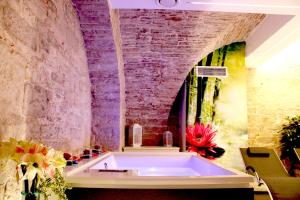 una vasca da bagno in una camera con parete in mattoni di Rubis Relais & SPA a Ruvo di Puglia