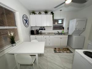 eine Küche mit einem weißen Tisch und einem weißen Kühlschrank in der Unterkunft Flamingo Studio - 5 min to Beach in Fort Lauderdale