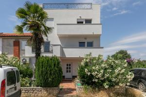 a white house with a palm tree in front of it at Apartments Korana in Pula