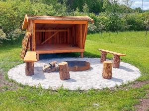 a fire pit with a wooden shelter and two benches at 8 person holiday home in Glesborg in Glesborg