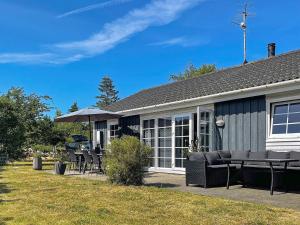 10 person holiday home in rsted في Ørsted: منزل به فناء وبه كراسي ومظلة