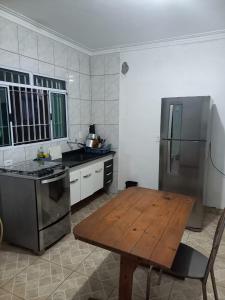 La cuisine est équipée d'une table en bois et d'un réfrigérateur en acier inoxydable. dans l'établissement Casa Térrea, Biu2planet, à Mongaguá 12 autres photos