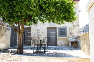 een tafel en stoelen onder een boom voor een gebouw bij 500 Home in Castrignano deʼ Greci