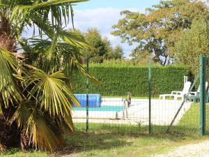 einen Zaun vor einem Pool mit einer Palme in der Unterkunft Gîte Lamonzie-Saint-Martin, 6 pièces, 8 personnes - FR-1-616-126 in Lamonzie-Saint-Martin