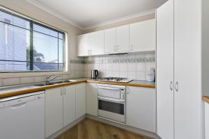 a white kitchen with white cabinets and a sink at A Stones Throw in Metung