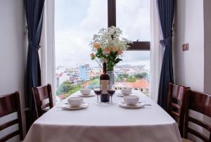 stół z wazonem kwiatów i oknem w obiekcie SALA HOTEL MÓNG CÁI w mieście Móng Cái