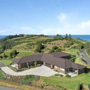 an aerial view of a house on a hill with the ocean at TuiRidge Tutukaka in Tutukaka