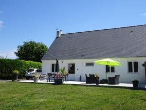 ein weißes Haus mit einem Tisch und einem Regenschirm in der Unterkunft Comfortable Bungalow, Pink Granite Coast in Pleumeur-Bodou