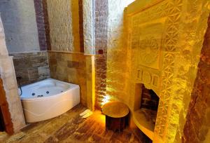a bathroom with a bath tub in a room with a fireplace at Larissa Cave Hotel in Nevsehir