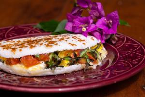 a sandwich on a purple plate with purple flowers at Pousada Beira Mar in Caraíva +28 photos