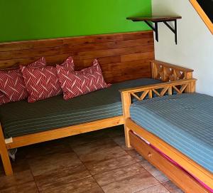 a wooden bed with red and white pillows on it at AMANECER DE MONTAÑA in Capilla del Monte