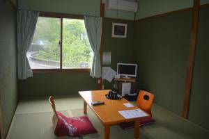 Drive Inn Keigetsu في تووادا: غرفة مع طاولة ومكتب مع نافذة