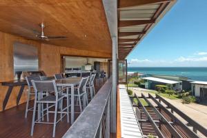 a balcony with a table and chairs and the ocean at Tangalooma Hilltop Haven in Tangalooma