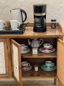 a coffee maker and cups on a wooden shelf at minivilla in Ash Shuwaybiţ