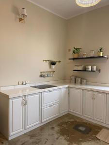 a kitchen with white cabinets and a sink at minivilla in Ash Shuwaybiţ