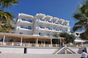 a large white building on the beach with palm trees at Coral Hotel & Resort in Vlorë