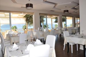 a restaurant with white tables and chairs and windows at Coral Hotel & Resort in Vlorë