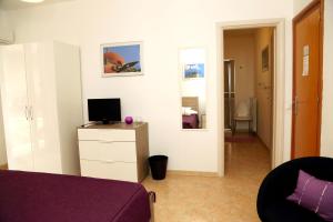 a room with a bed and a tv on a dresser at B&B Siciliò in Santa Flavia