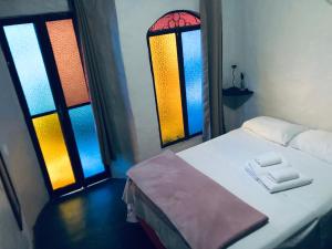 a room with a bed and two windows with towels at Shanti - Hospedaria na Vila de São Jorge in Sao Jorge