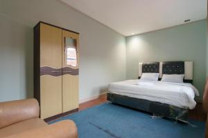 a small bedroom with a bed and a couch at Asokatama Residence Syariah Mitra RedDoorz in Padang