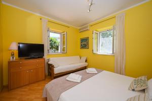 Camera gialla con 2 letti e una TV di Apartment La Rocca a Dubrovnik