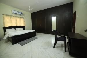 a bedroom with a bed and a desk and a chair at Royal Home Stay deluxe Room in Tirupati